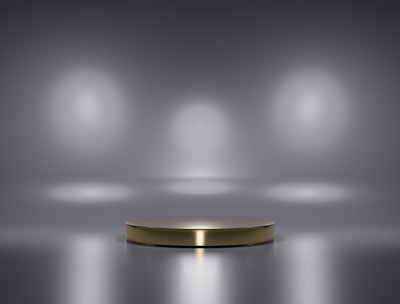 A metallic platform is centered in a minimalistic setting with a reflective surface. Soft, diffused lighting creates circular patterns on the background wall, enhancing the focus on the central stage. The ambiance is sleek and modern, with a hint of elegance.