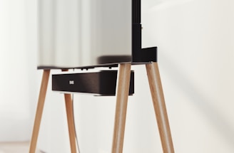 A modern television set up on sleek, angled wooden legs with a soundbar positioned directly beneath it. The design is minimalist and stylish, integrating functionality with aesthetics in a clean, contemporary space.